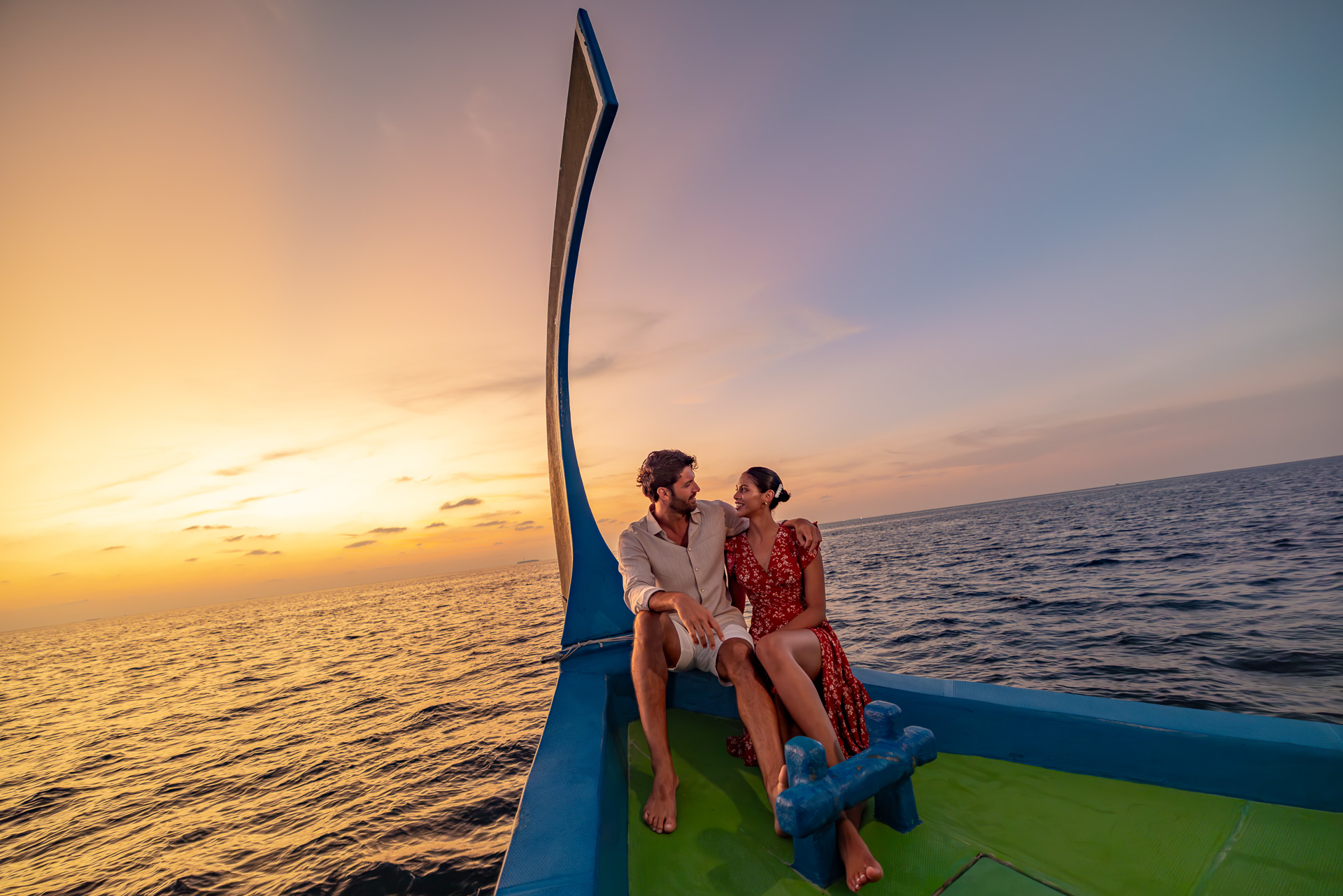 Guests enjoying a sunset cruise at OZEN LIFE MAADHOO, taking in views across the Indian Ocean as the sun sets over South Malé Atoll.