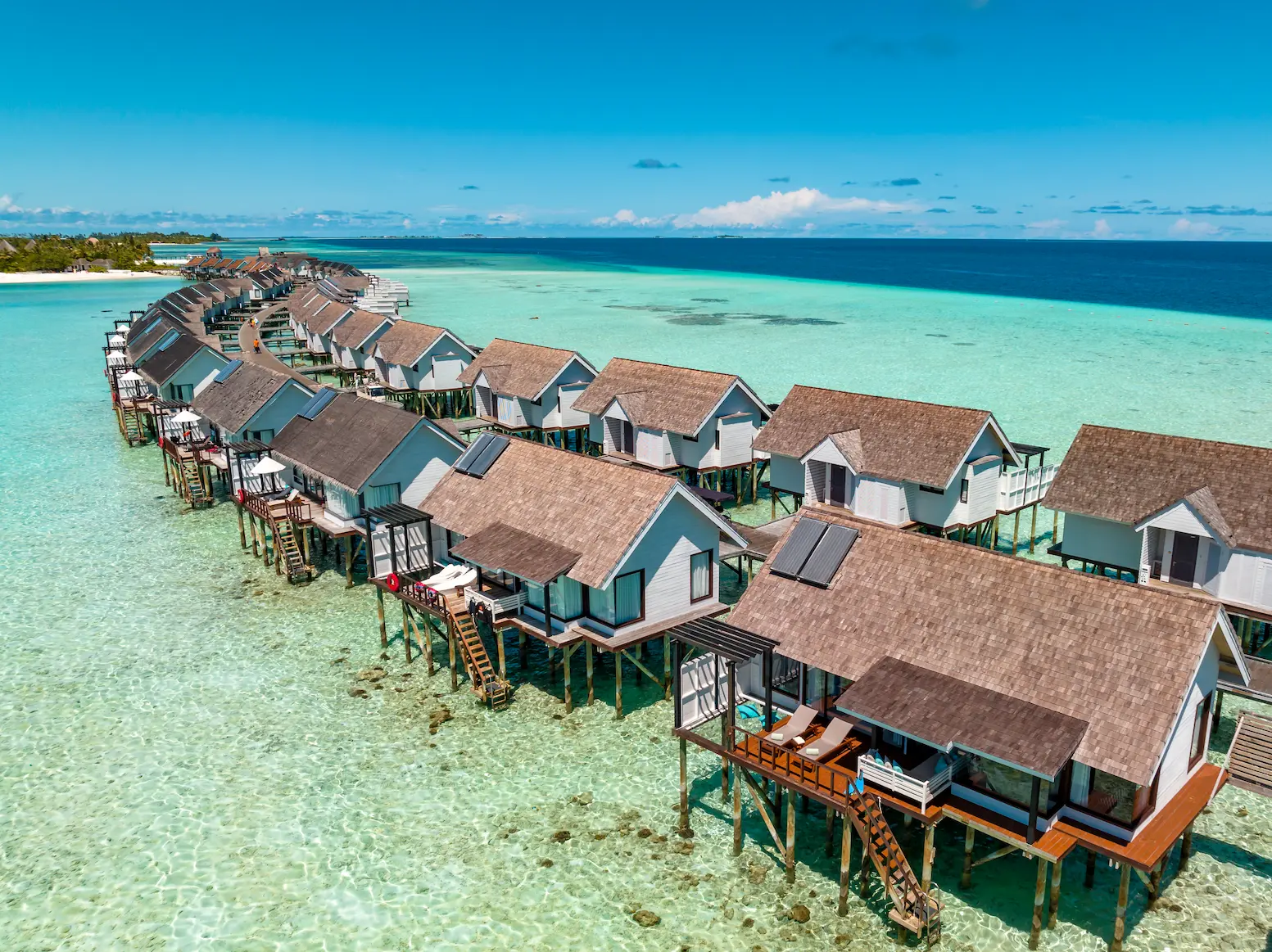 Aerial view of Wind Villas at OZEN LIFE MAADHOO, showing the overwater accommodation extending across the lagoon with direct access to the surrounding waters