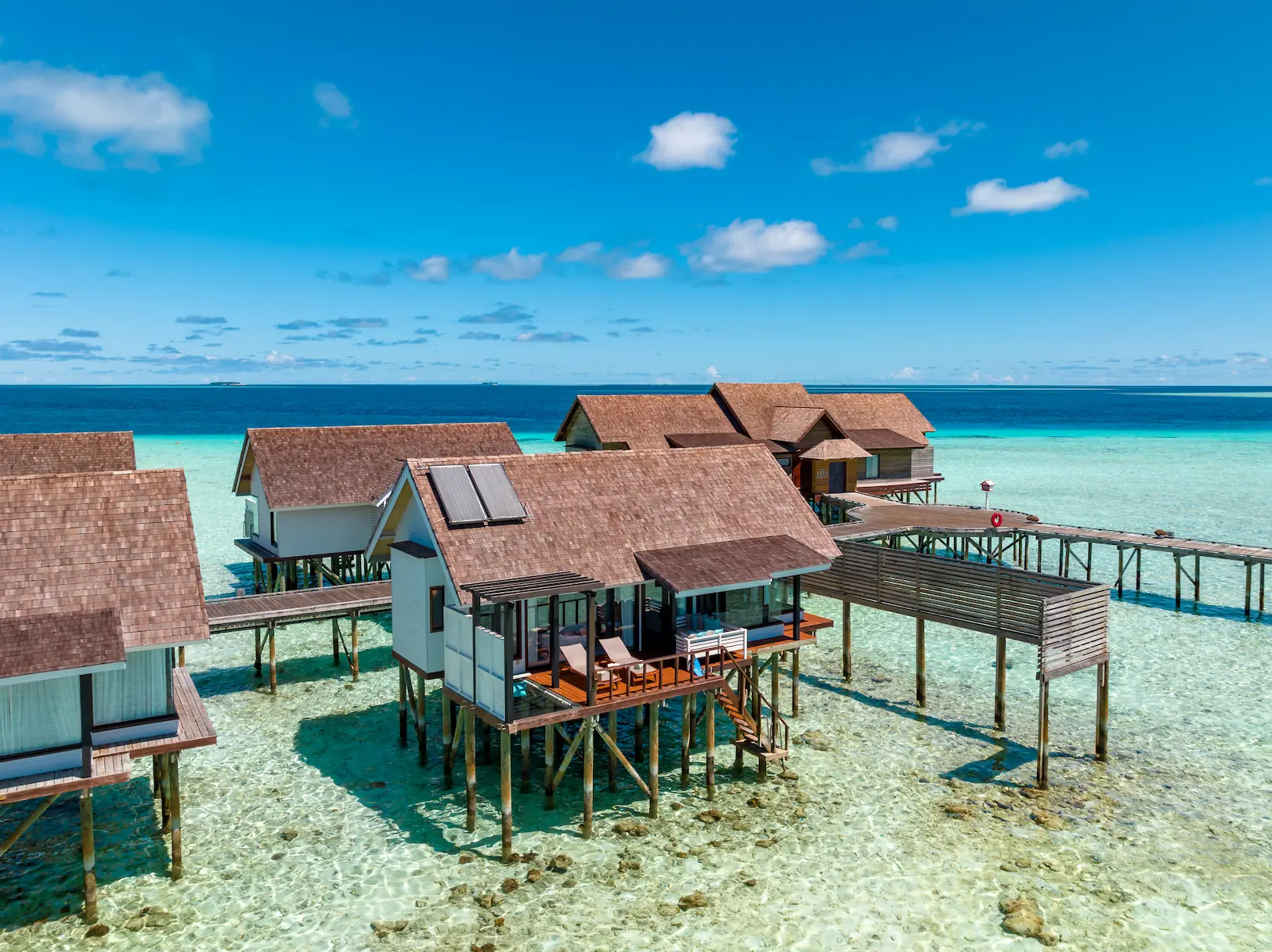 Aerial view of Wind Villas at OZEN LIFE MAADHOO extending over the lagoon, showcasing the overwater accommodation layout and direct access to the surrounding waters