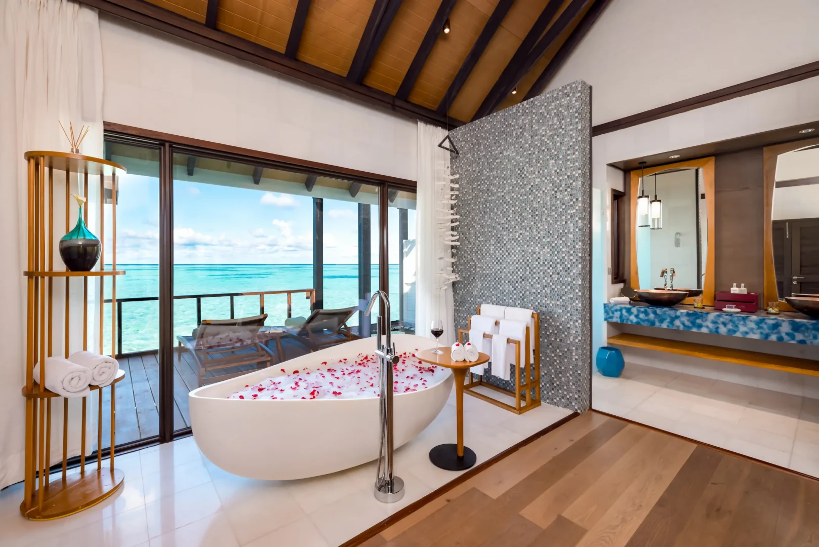 Spacious bathroom in a Wind Villa at OZEN LIFE MAADHOO featuring a freestanding bathtub with views across the lagoon and contemporary overwater villa design
