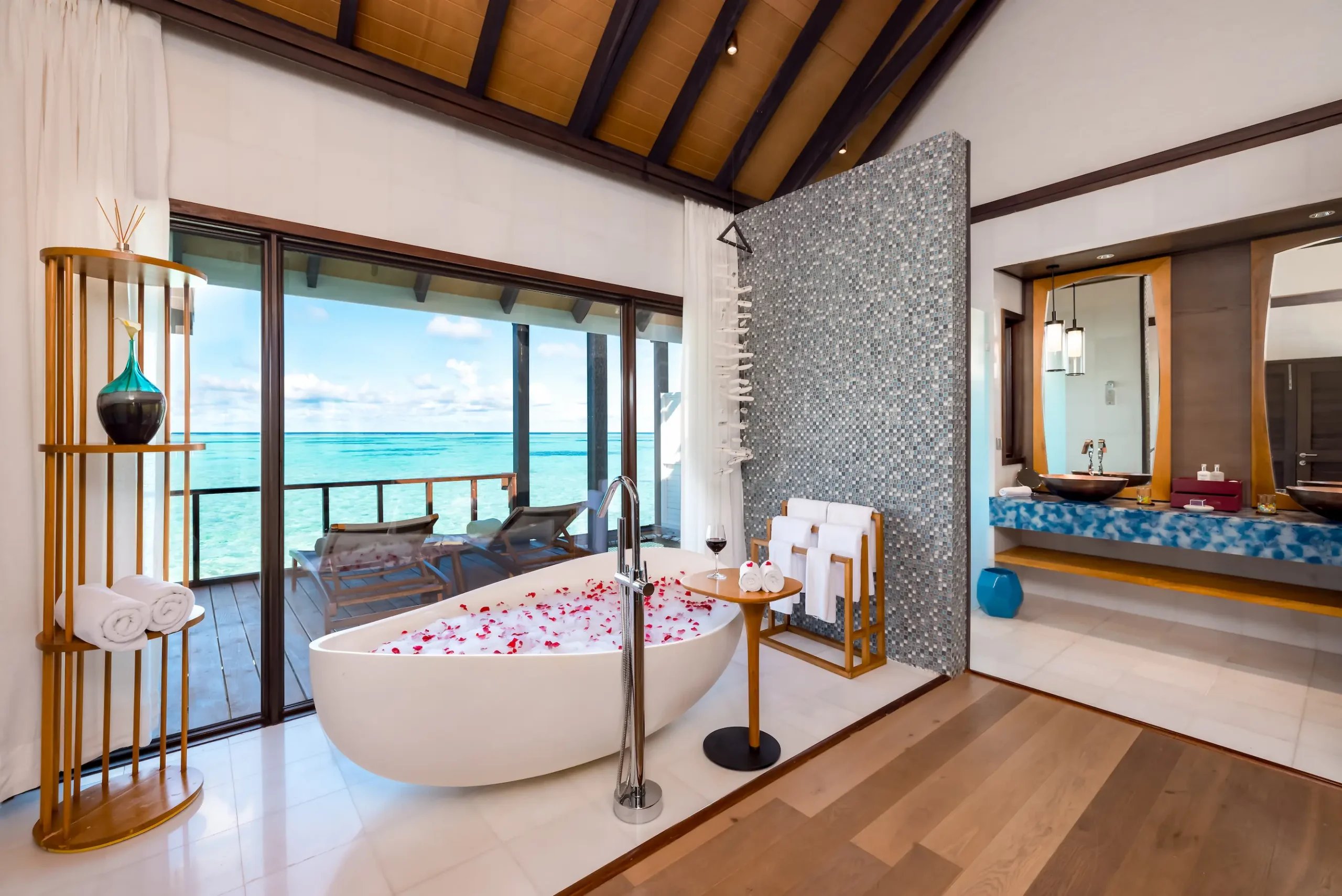 Spacious bathroom in a Wind Villa at OZEN LIFE MAADHOO featuring a freestanding bathtub with views across the lagoon and contemporary overwater villa design