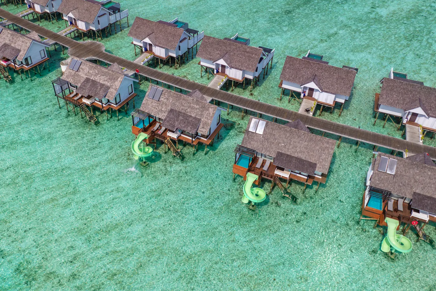 Aerial exterior view of a Wind Villa with Jacuzzi & Slide at OZEN LIFE MAADHOO, highlighting the overwater location, private Jacuzzi, waterslide and direct lagoon access