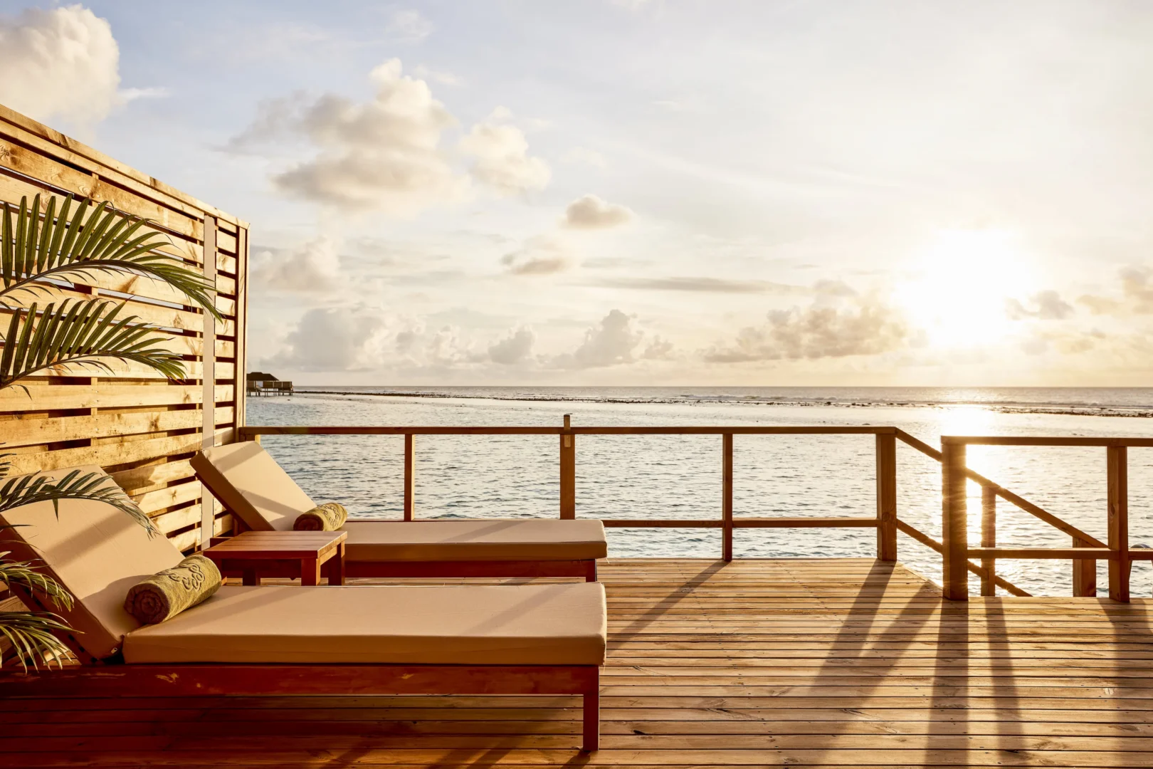 sun loungers on the terrace of a grand water villa at sun siyam olhuveli maldives overlooking the lagoon