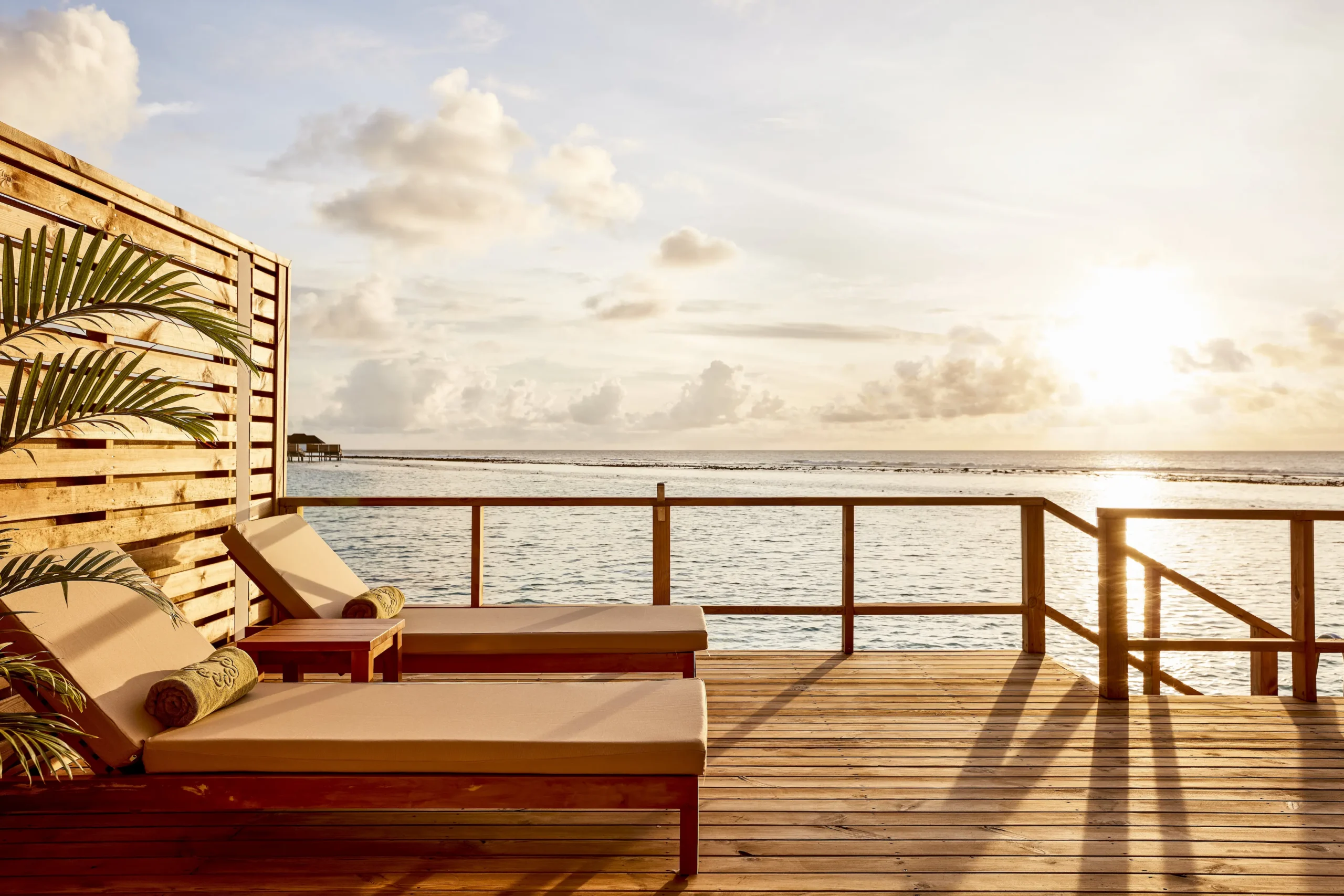 sun loungers on the terrace of a grand water villa at sun siyam olhuveli maldives overlooking the lagoon