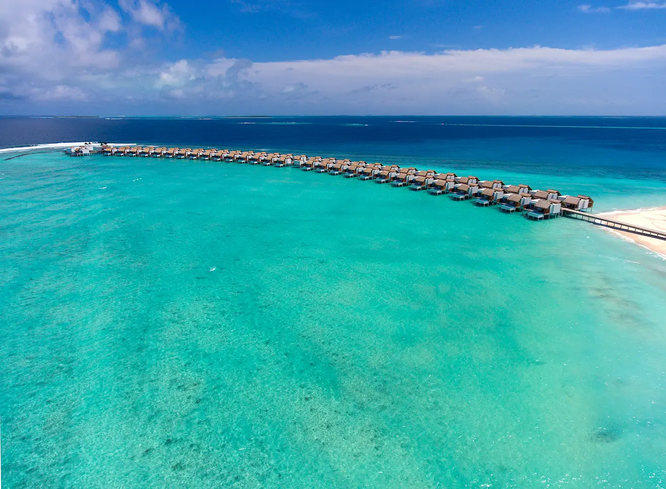 aerial view of the lagoon at emerald maldives resort & spa in the maldives showcasing overwater villas, white sand beaches and crystal-clear waters