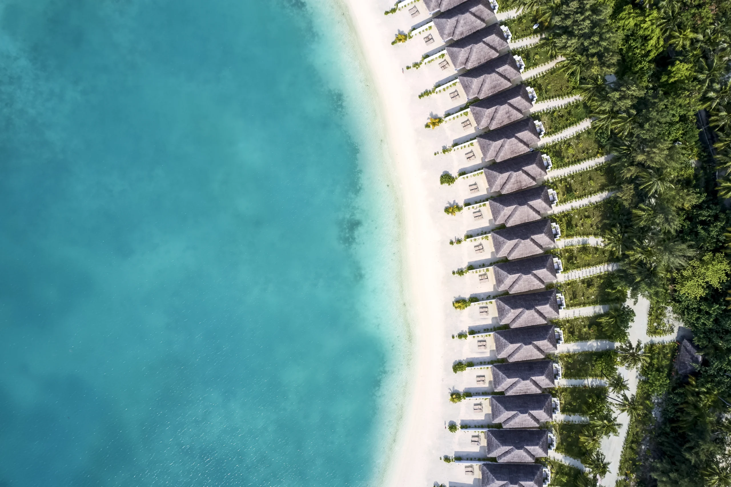 aerial view of grand beach villas at sun siyam olhuveli maldives positioned along the beachfront and surrounded by island landscapes
