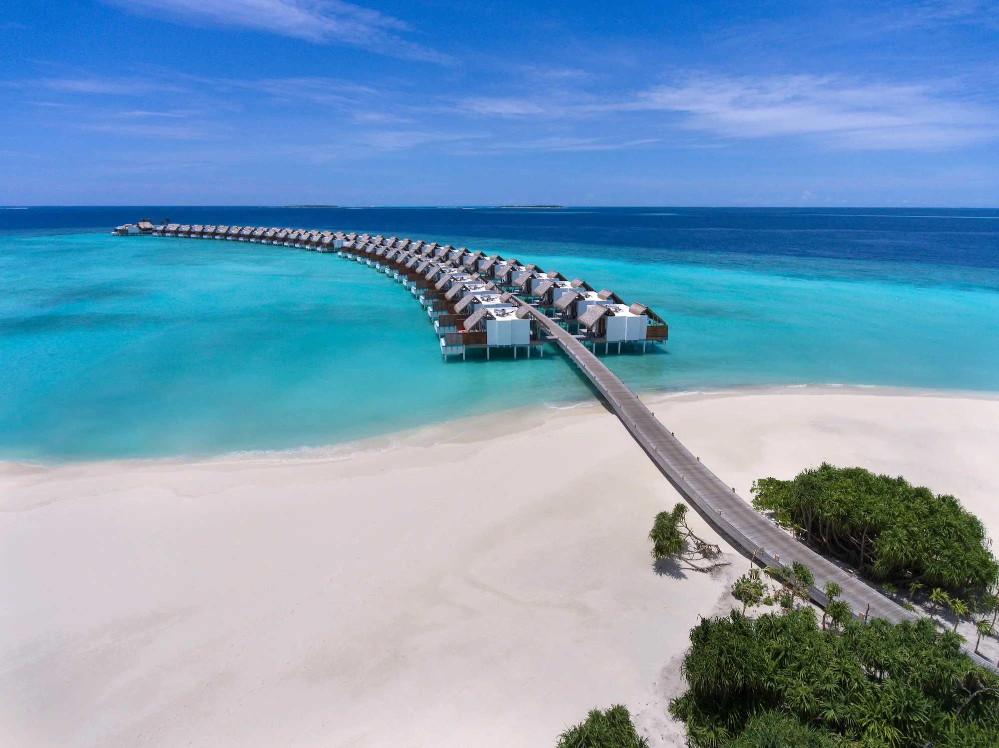 aerial view of water villas at emerald maldives resort & spa in the maldives extending across the lagoon with direct access to the ocean