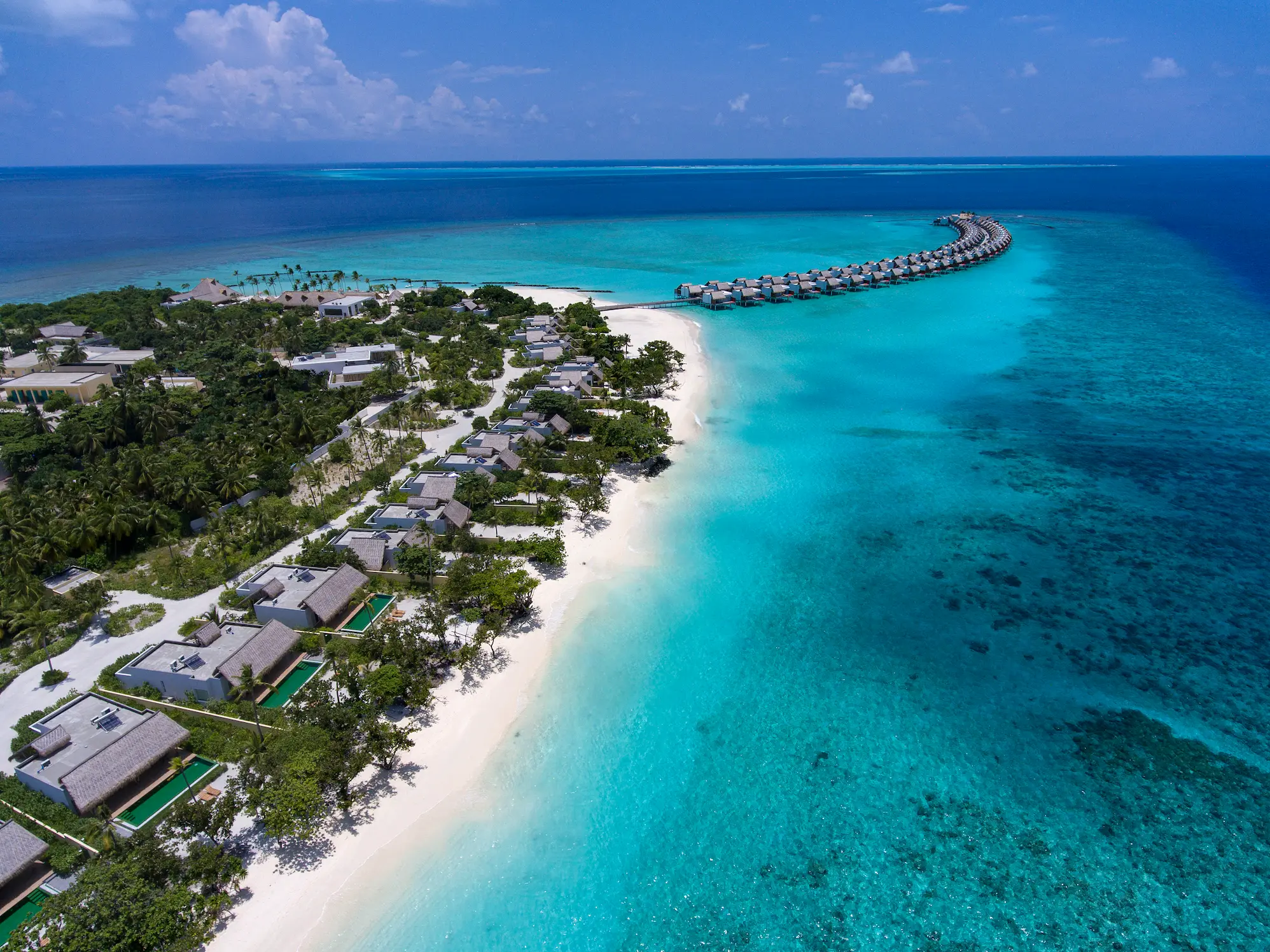aerial view of family beach villas with pool at emerald maldives resort & spa in the maldives surrounded by white sand beaches, tropical greenery and lagoon waters