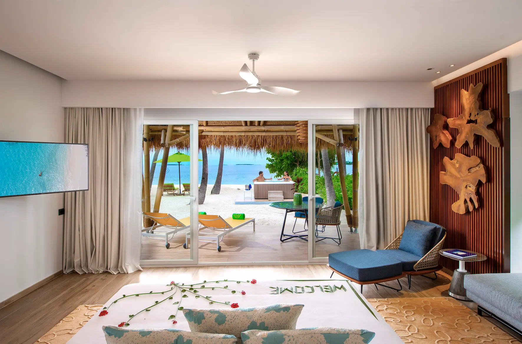 bedroom view from a jacuzzi beach villa at emerald maldives resort & spa in the maldives overlooking the outdoor terrace and surrounding beach setting