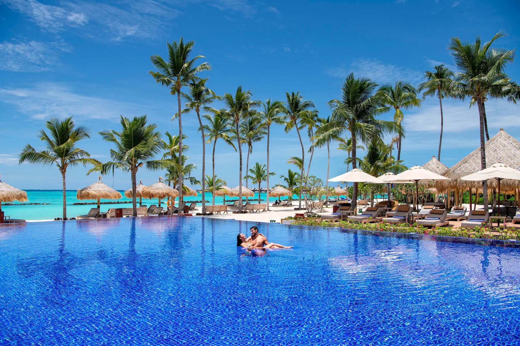 main swimming pool at emerald maldives resort & spa in the maldives overlooking the lagoon with sun loungers and ocean views
