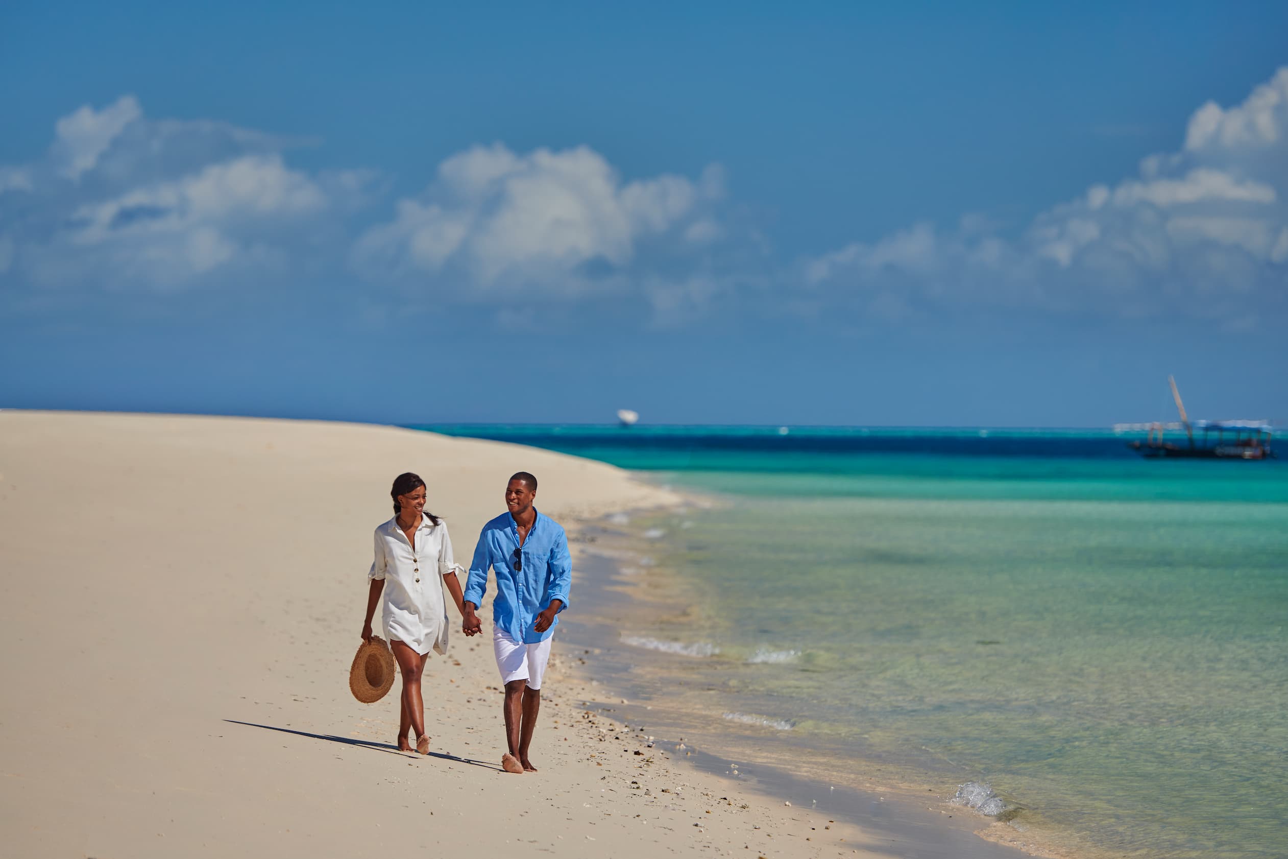 Guests walking along the beach near Park Hyatt Zanzibar with views of the Indian Ocean and Stone Town waterfront.