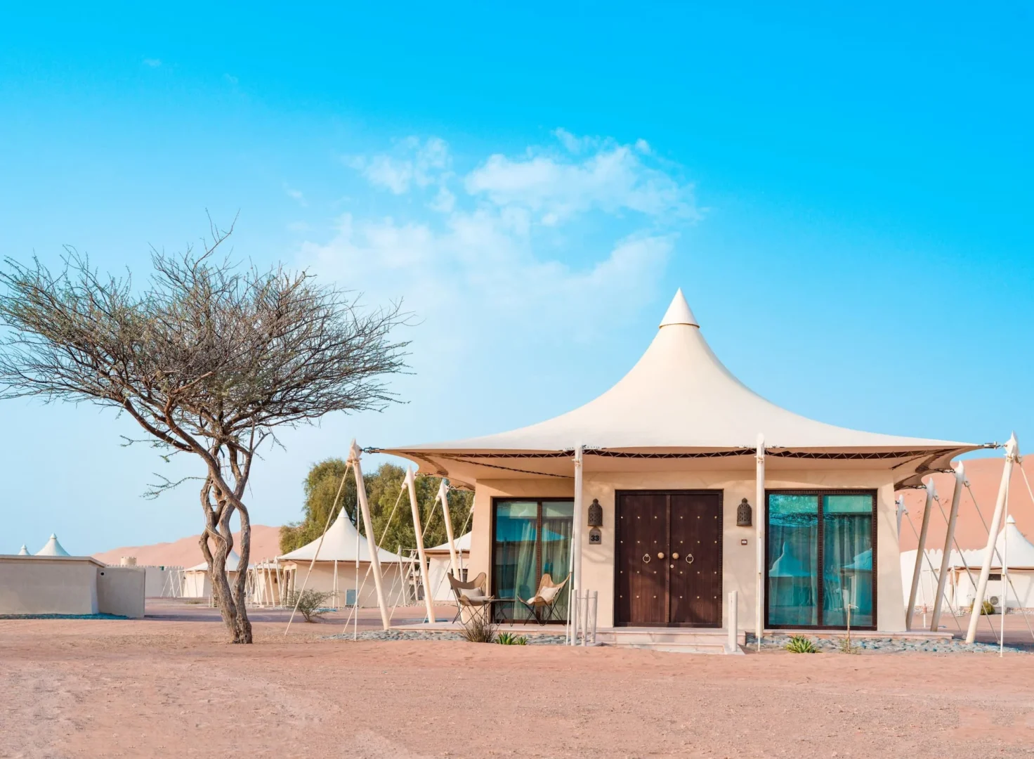 Exterior view of a Premier Villa at Desert Nights Resort Oman surrounded by the dunes of the Wahiba Sands desert