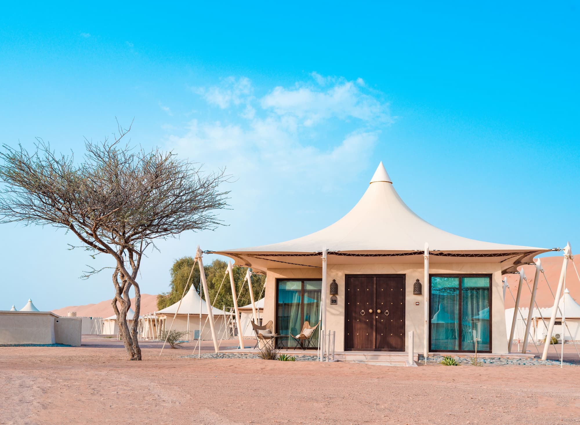 Exterior view of a Premier Villa at Desert Nights Resort Oman surrounded by the dunes of the Wahiba Sands desert